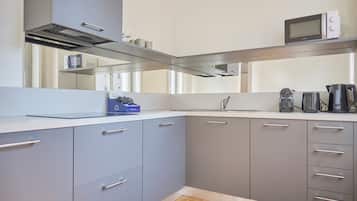 Una cucina moderna con mobili grigi, una cappa aspirante in acciaio inossidabile, un forno a microonde e una macchina da caffè.