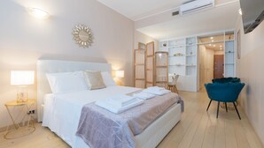 Una habitación de hotel con una cama grande, mesitas de noche, una silla y un armario.