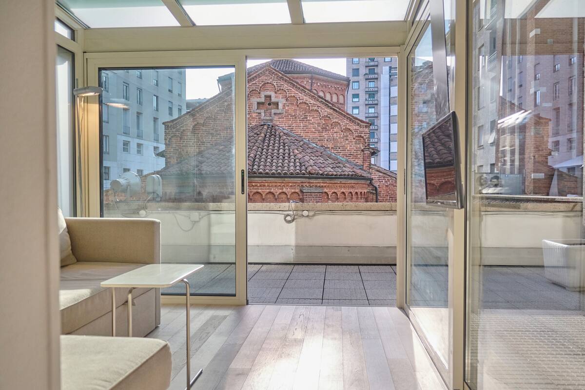 Un interior moderno con una pared de vidrio que ofrece vistas a un edificio histórico.