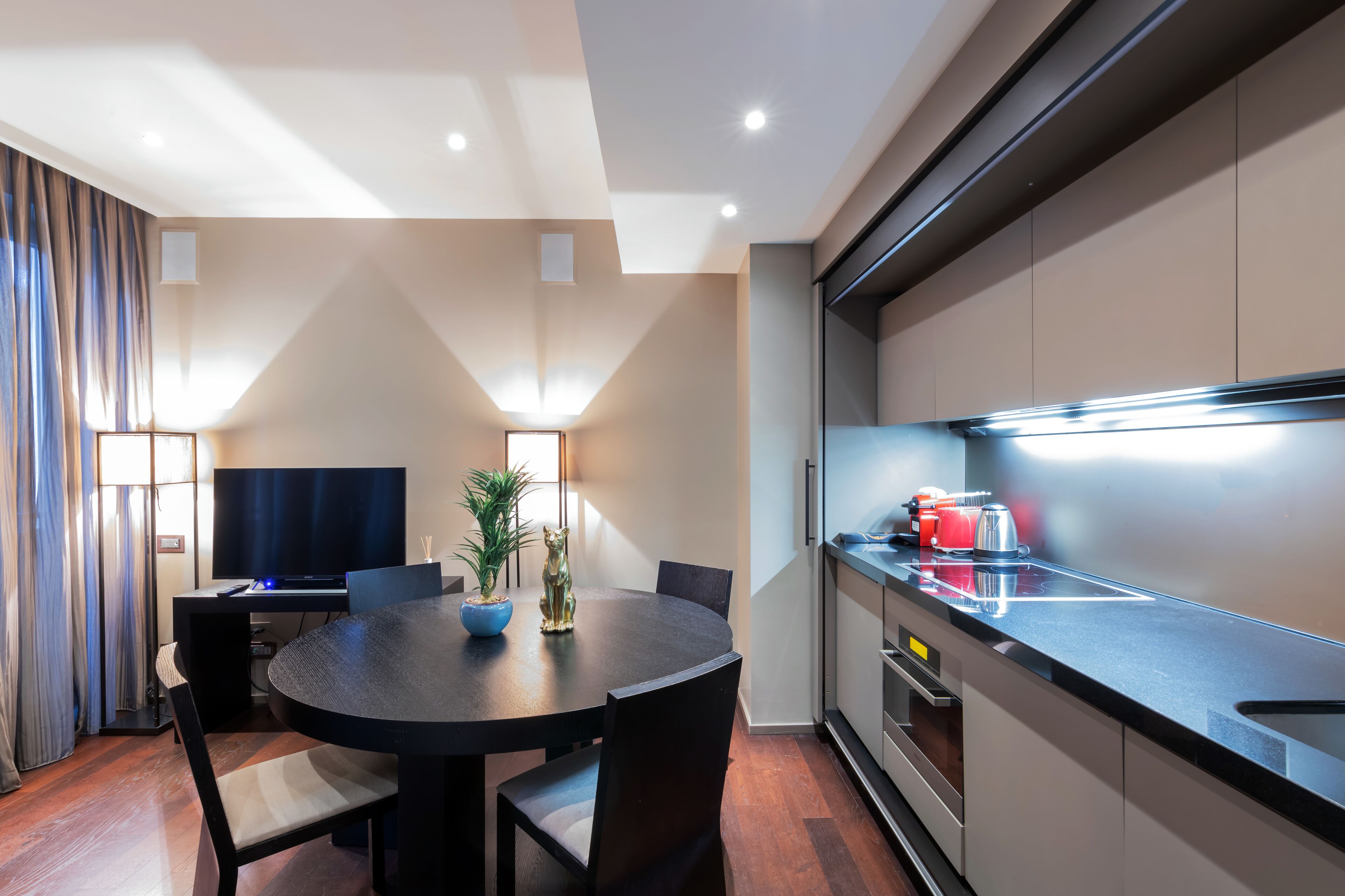 A modern kitchen with a black countertop, stainless steel appliances, and a dining area with a round table and chairs.