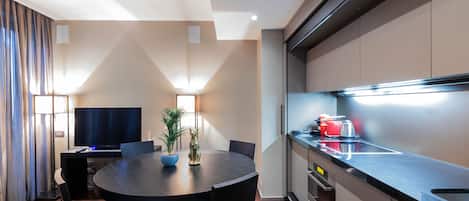 A modern kitchen with a black countertop, stainless steel appliances, and a dining area with a round table and chairs.
