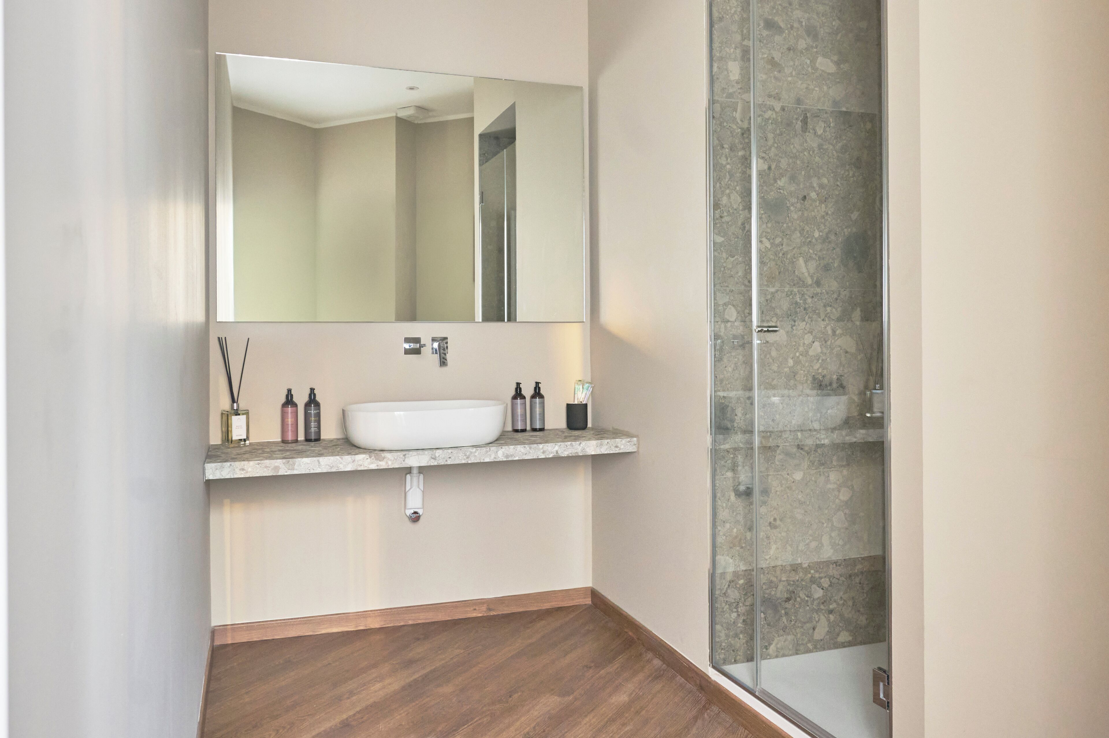 A bathroom with a white sink, mirror, and shower.