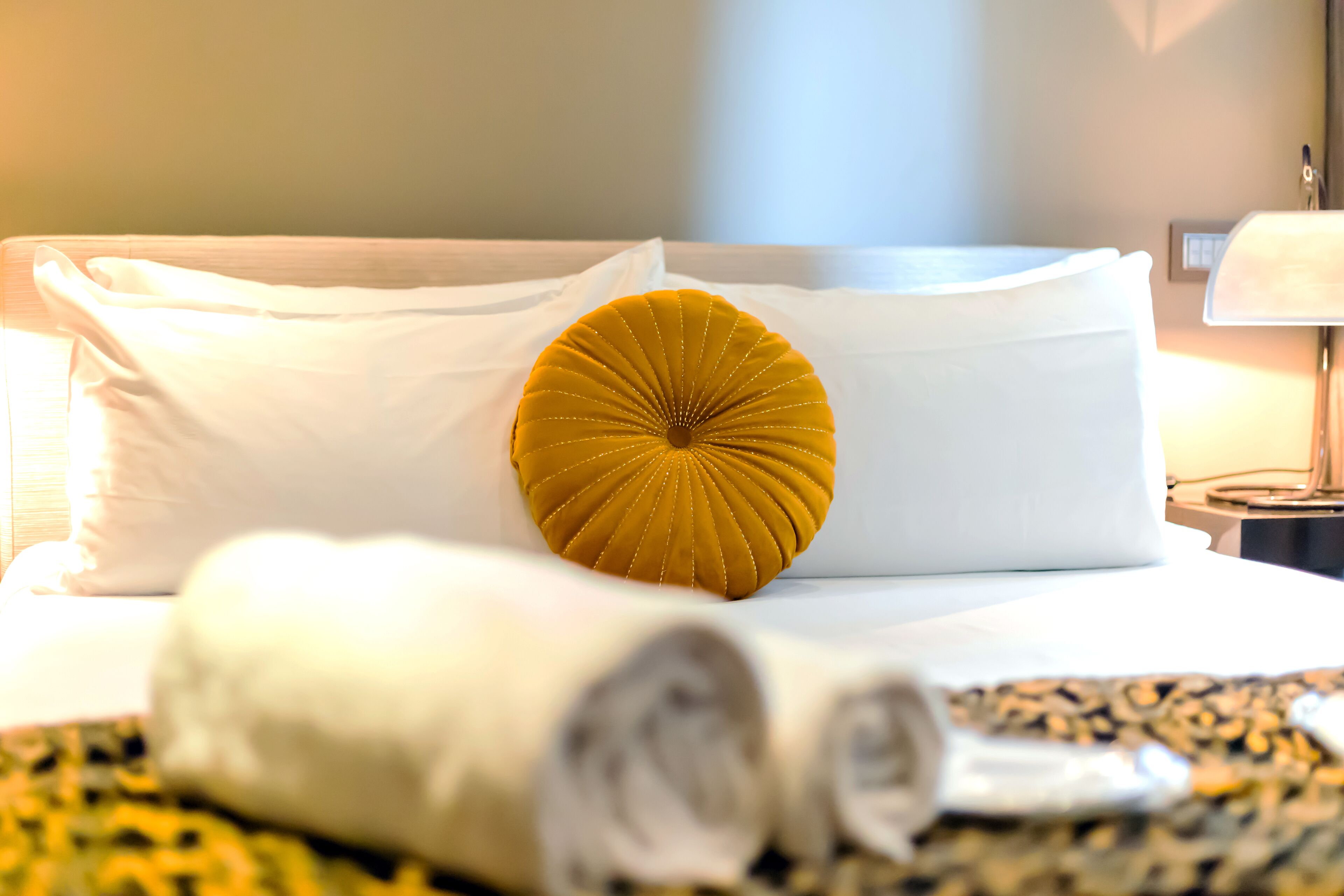 Un lit bien fait, avec du linge de lit blanc et un seul coussin décoratif.