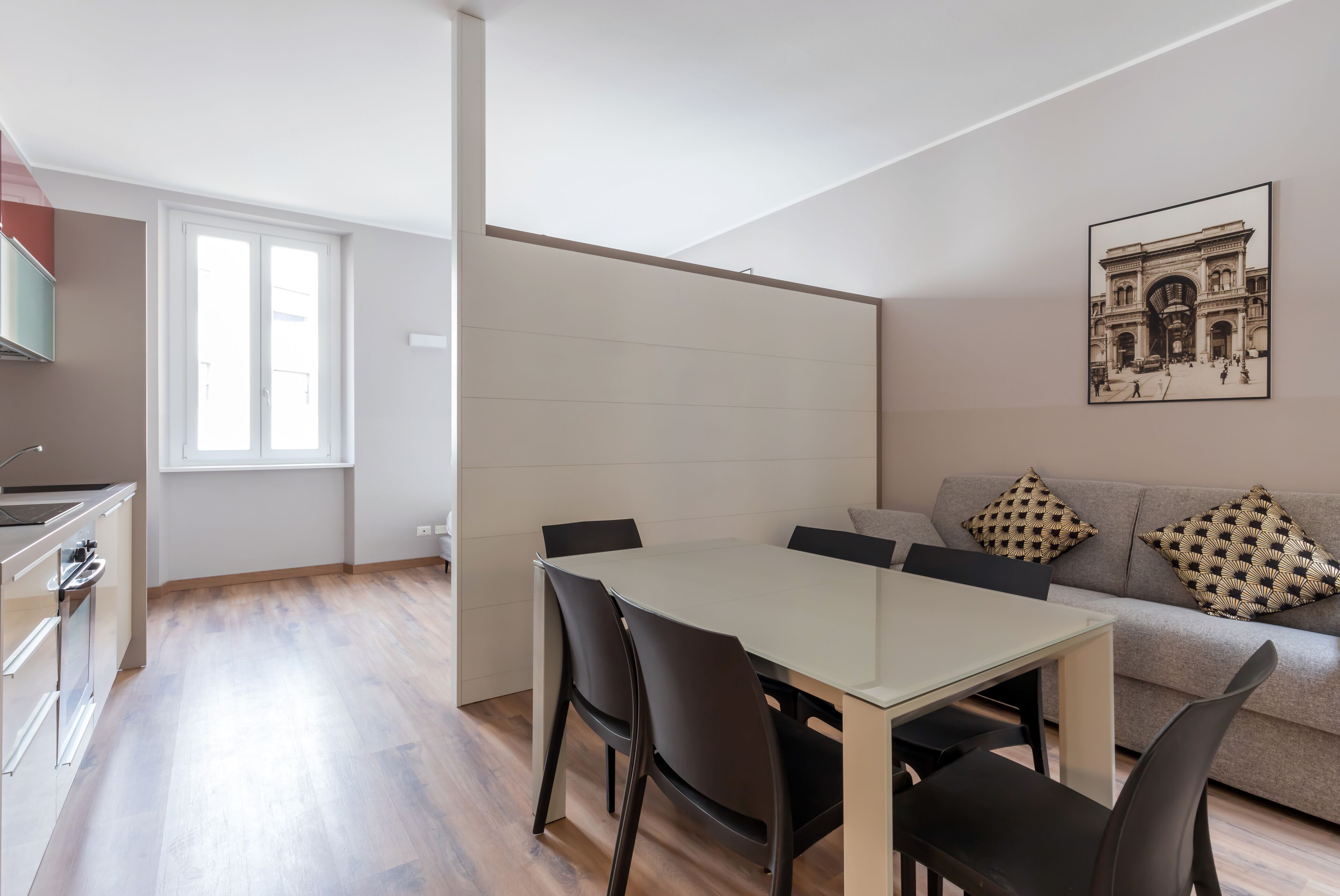 Un espacio moderno de estar con comedor, cocina y un sofá con cojines estampados.