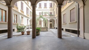 Un patio con columnas, plantas en macetas y una fuente central.