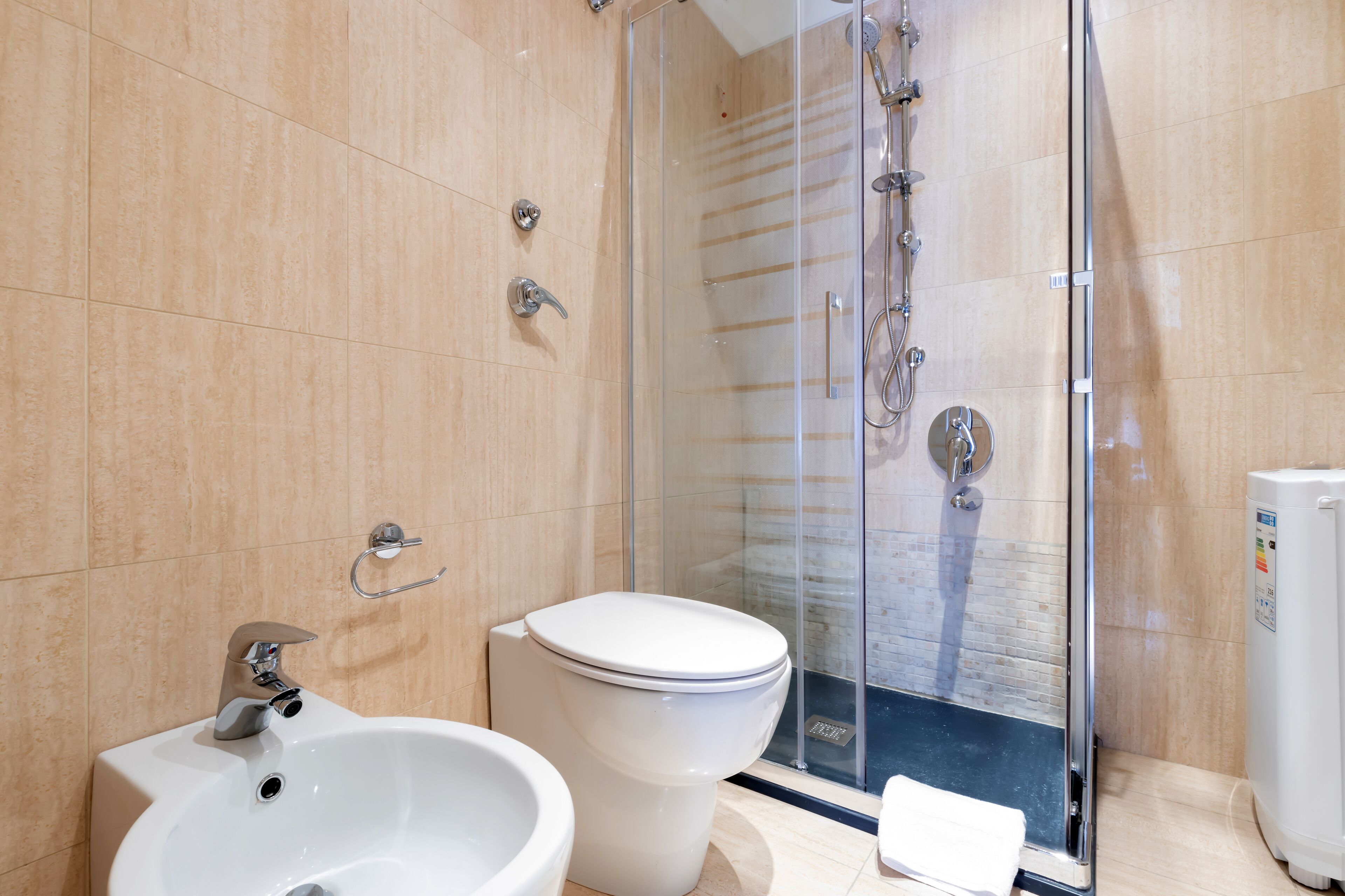 A modern bathroom with a glass-enclosed shower, a white sink, and a toilet.