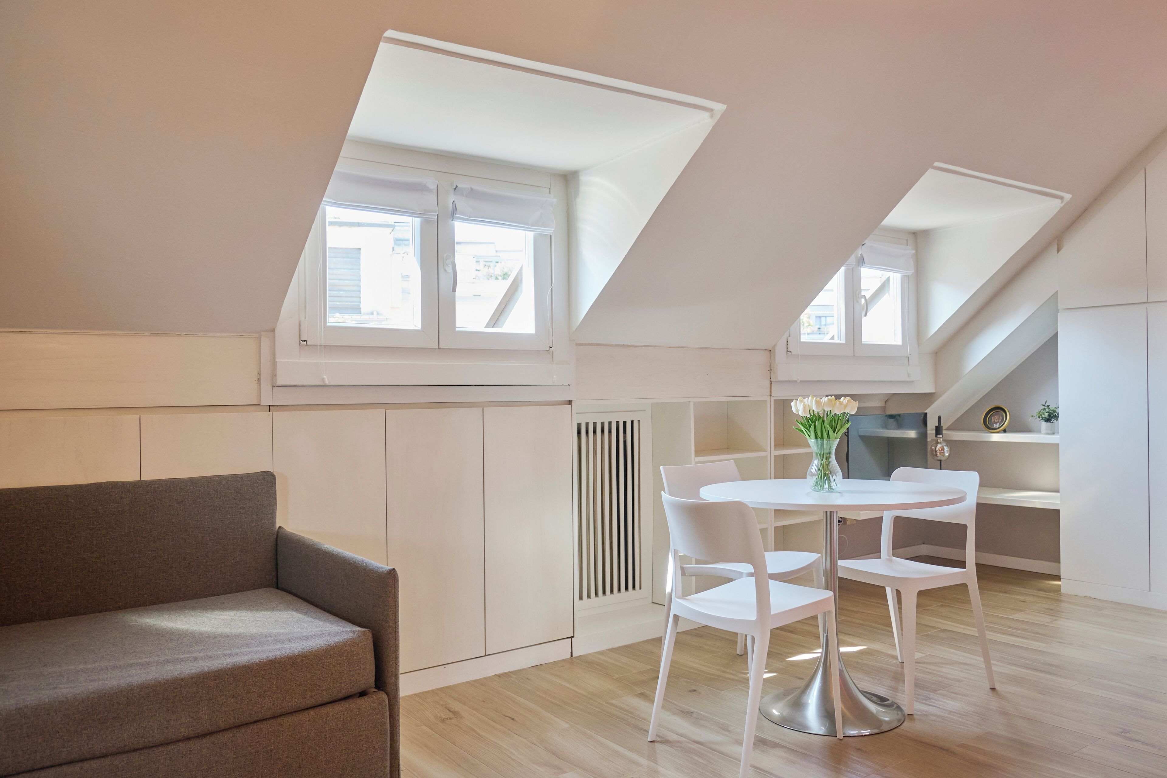 A modern loft apartment with a dining area, a sofa, and a kitchen.