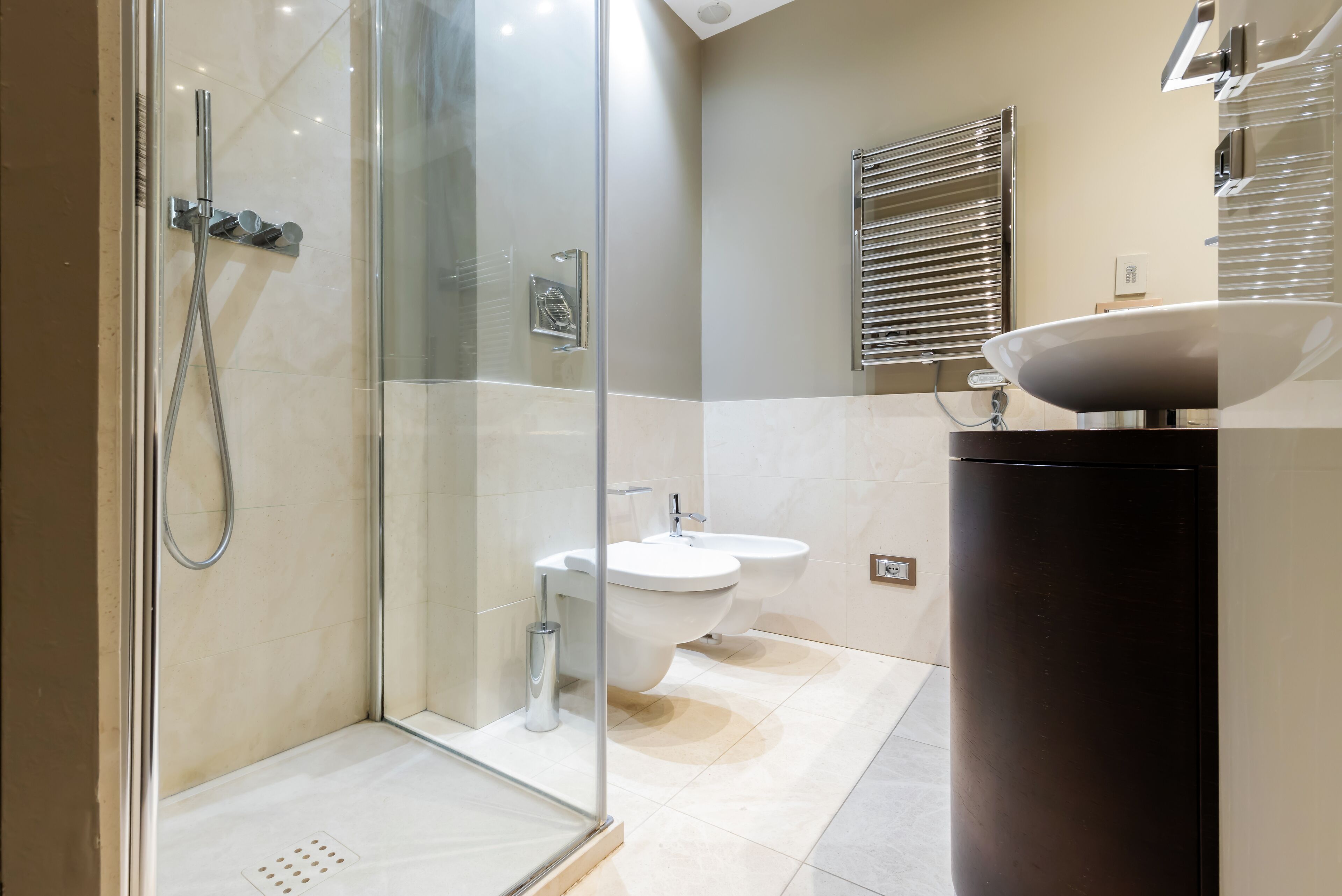 A modern bathroom with a glass-enclosed shower, a sink, and a bidet.