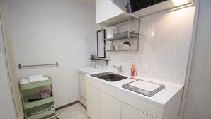 A small kitchen with white cabinets, a double sink, and a green storage cart. - Grande Shagi GS206 (Osaka)