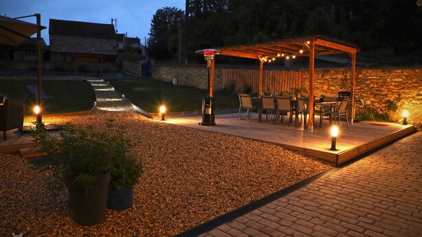 A patio area with a pergola, seating, and a pathway leading to a house. - La Belle Tuilière: A Charming Home in Champagne.  (Vandières)