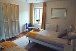 A bedroom with a bed, a chair, a wardrobe, a window with curtains, and a radiator. - La Belle Tuilière, a charming residence in Champagne (Vandières)
