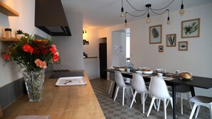 A modern kitchen with a wooden table, white chairs, and a vase of flowers. - La Belle Tuilière: A Charming Home in Champagne.  (Vandières)