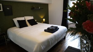 A neatly made bed with white and black bedding, a bedside lamp, and a vase with flowers on the right side. - La Belle Tuilière: A Charming Home in Champagne.  (Vandières)