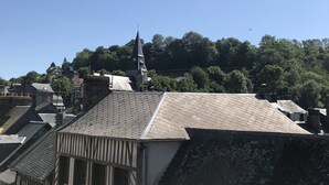 Une vue d’une ville avec un clocher d’église imposant, des bâtiments traditionnels et une rivière.