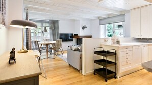 Una cocina moderna con armarios blancos, un comedor con mesa y sillas, y una pequeña isla con pileta.