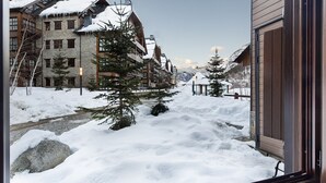 Calle nevada con edificios, una valla de madera y una montaña al fondo.