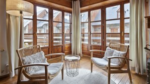 A cozy room with large windows, wooden furniture, and a view of neighboring buildings. - Luderna - Apartamento con terraza Orri A3 (Gessa)