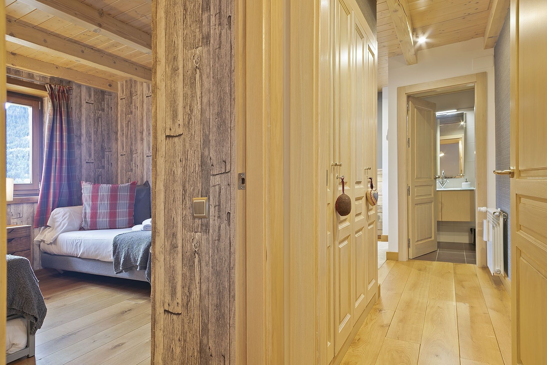 A wooden interior with a bed, a wardrobe, and a bathroom visible through an open door.