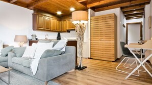 En moderne stue med en grå sofa, træloft og et spiseområde med bord og stole.