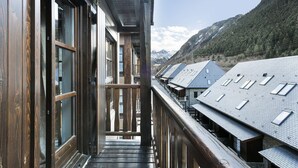 A wooden balcony with a view of a row of buildings with sloped roofs and skylights. - Luderna - Apartamento Val de Ruda B1 Morèdo (Baqueira)