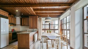 A spacious kitchen with wooden cabinets, a central island, and large windows providing natural light. - Luderna - Apartamento Val de Ruda B1 Morèdo (Baqueira)