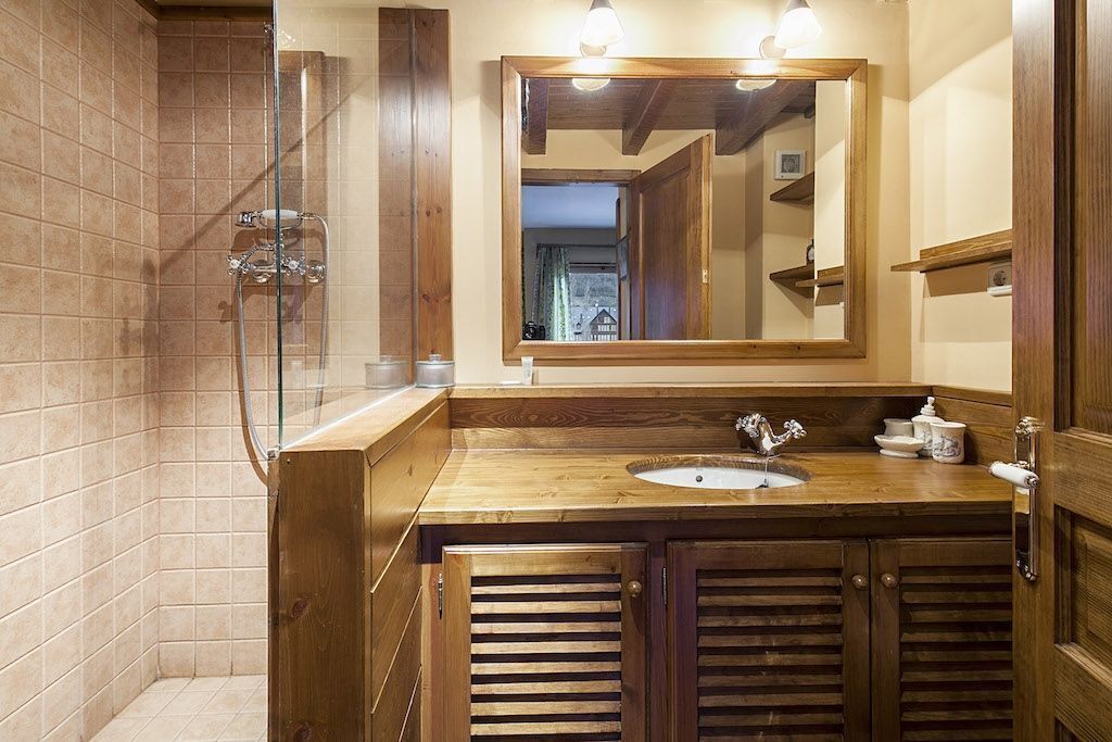 A bathroom with a wooden vanity, a mirror, and a shower enclosure.