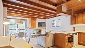 Une cuisine chaleureuse avec des meubles en bois, un coin repas comprenant une table et des chaises, et une cheminée.