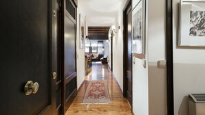A hallway with wooden flooring, a red patterned rug, and framed artwork on the walls. - Luderna - Apartamento con terraza Bonaigua B2 (Baqueira)