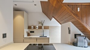 A modern kitchen with a black induction cooktop, wooden ceiling beams, and a built-in coffee machine.