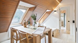 A dining area with a wooden table, chairs, and a view of the outdoors through a skylight.