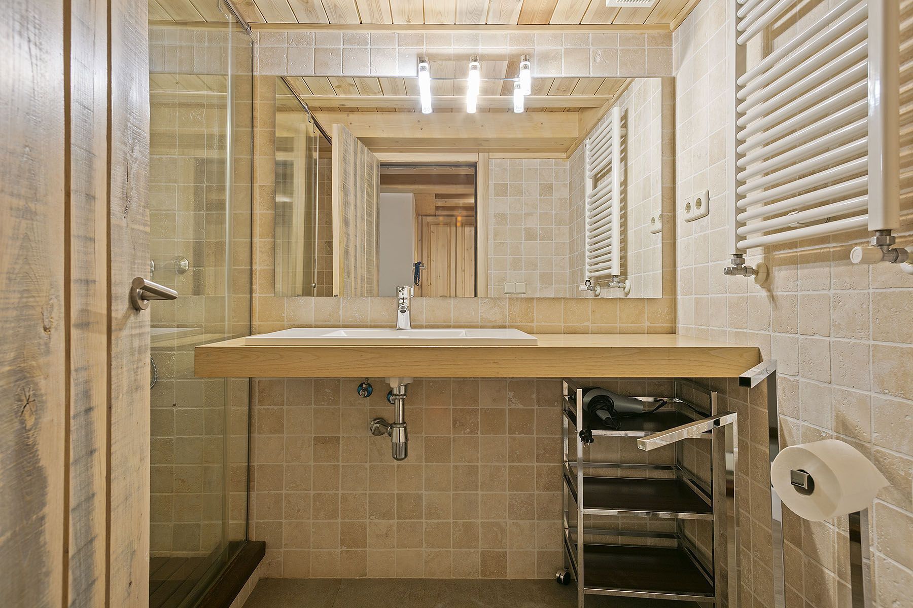 A bathroom with a wooden vanity, a mirror, a sink, and a towel rack.