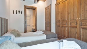 Een slaapkamer met twee bedden, houten kasten en een badkamer door een open deur zichtbaar.