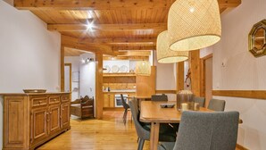 Un comedor de madera con mesa y sillas, un aparador de madera, y una cocina al fondo.