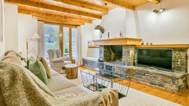 Una sala de estar acogedora con chimenea de piedra, vigas de madera en el techo y una zona de estar cómoda.