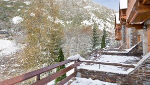Un edificio de piedra con balcones de madera que dan a una montaña nevada.