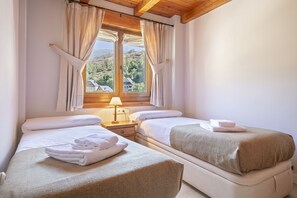 Habitación de hotel con dos camas, una ventana con cortinas, una lámpara y toallas sobre las camas.