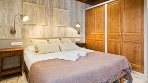 A bedroom with a large bed, wooden wardrobe, and two wall-mounted lamps. - Luderna - Apartamento Val de Ruda B2 Pradets (Baqueira)