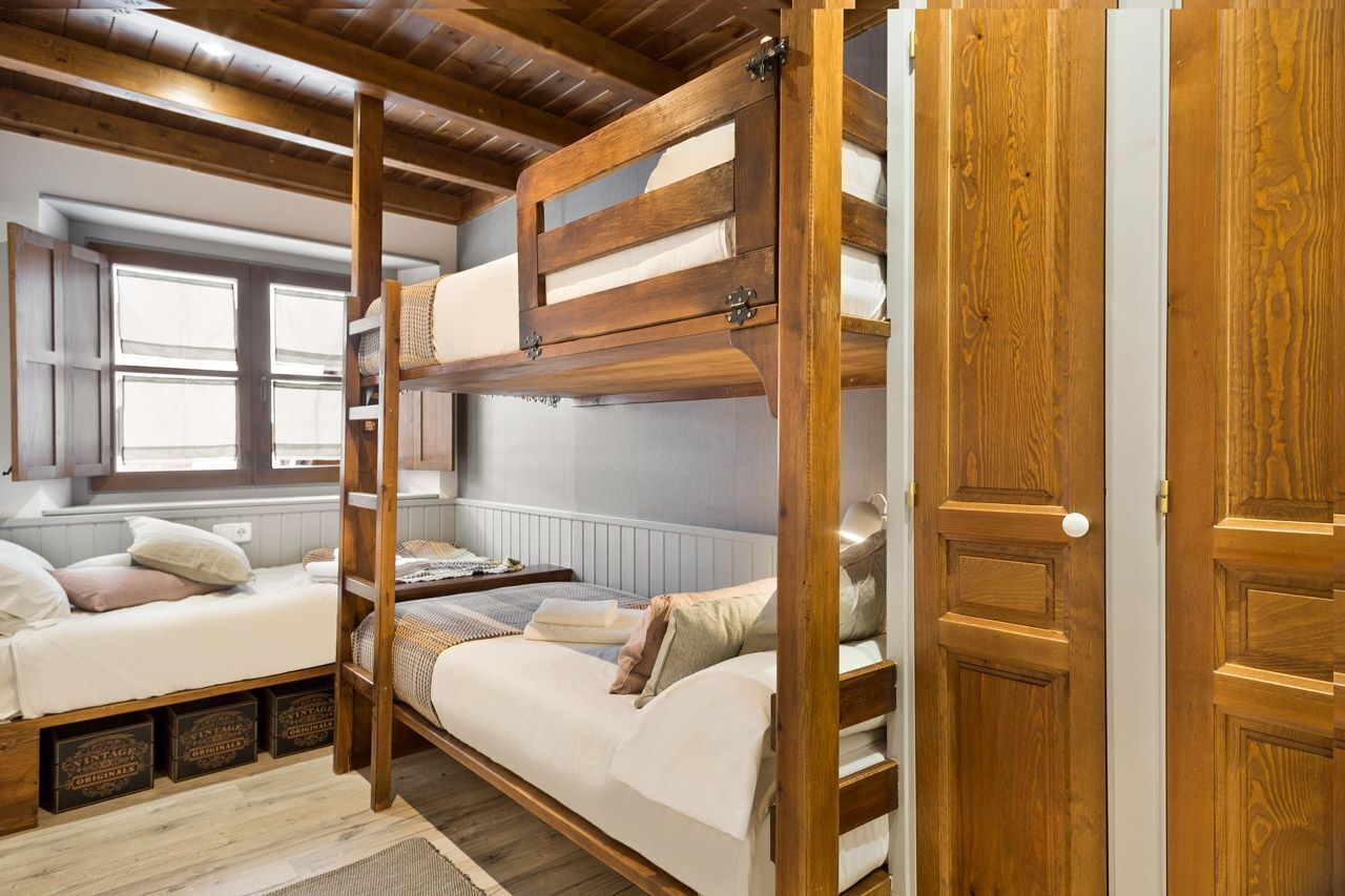 Ein Schlafzimmer mit Etagenbetten, Holzbalken, einem Fenster und einer Tür.