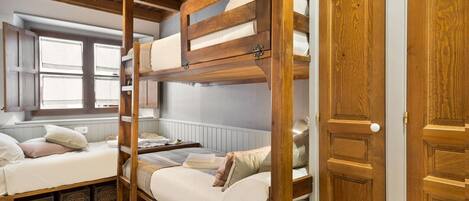 Ein Schlafzimmer mit Etagenbetten, Holzbalken, einem Fenster und einer Tür.