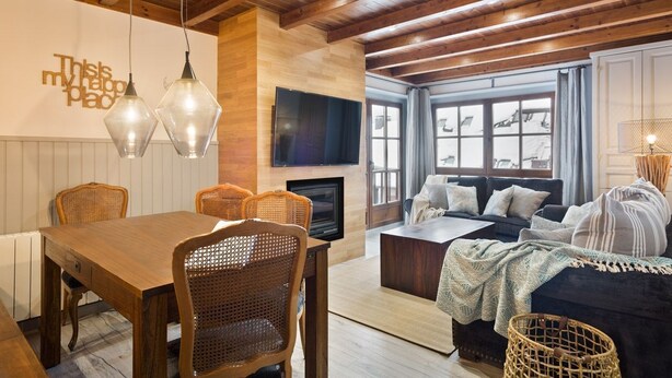 A cozy living room with a wooden ceiling, a fireplace, a TV, and a sofa with a view to the outside. - Luderna - Apartamento Val de Ruda B2 Pradets (Baqueira)