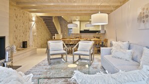 A spacious living area with a high ceiling, wooden beams, a dining area with a large table and chairs, and a cozy seating area with a sofa and armchairs. - Luderna - Casa Val de Ruda IV des Artiguetes (Baqueira)