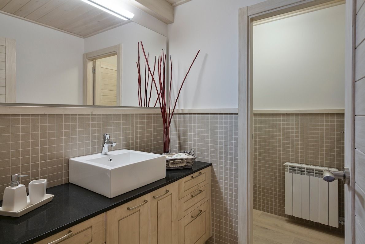 Une salle de bain moderne avec un lavabo blanc, des meubles en bois, un miroir et un radiateur.