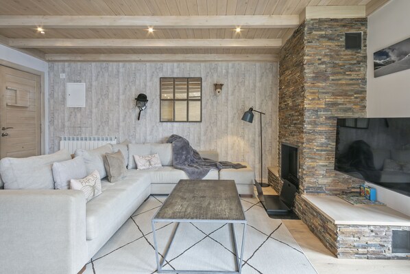 A modern living room with a stone fireplace, a white sofa, and a coffee table.