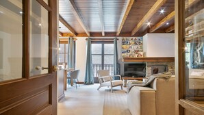 A cozy living room with a wooden ceiling, a sofa, a television, and a wall with pictures. - Luderna - Apartamento Val de Ruda B21 Blanhiblar (Baqueira)