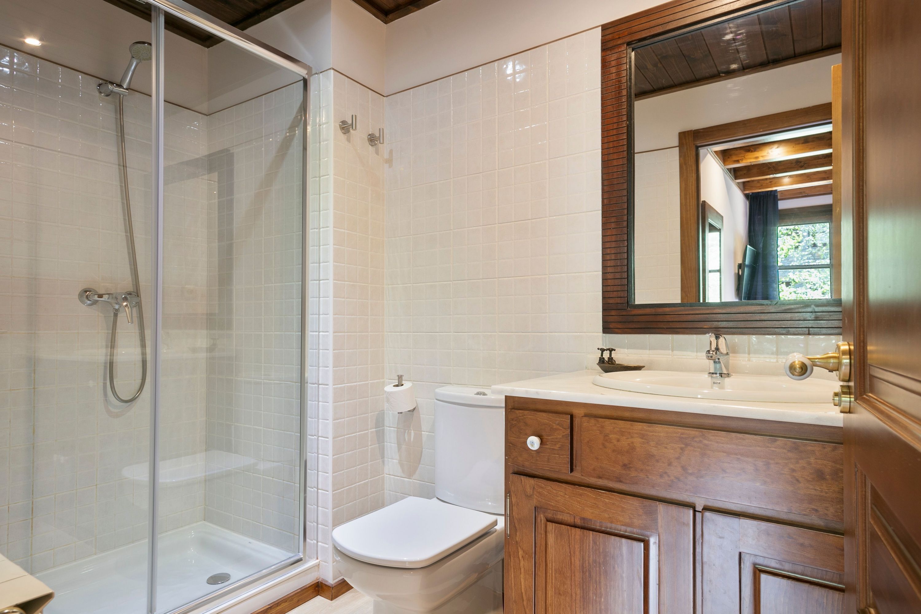 Un bagno con doccia vetrata, un water e mobili in legno.