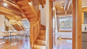 Ein Holzinnenraum mit Treppe, Essbereich und Blick durch ein Fenster.