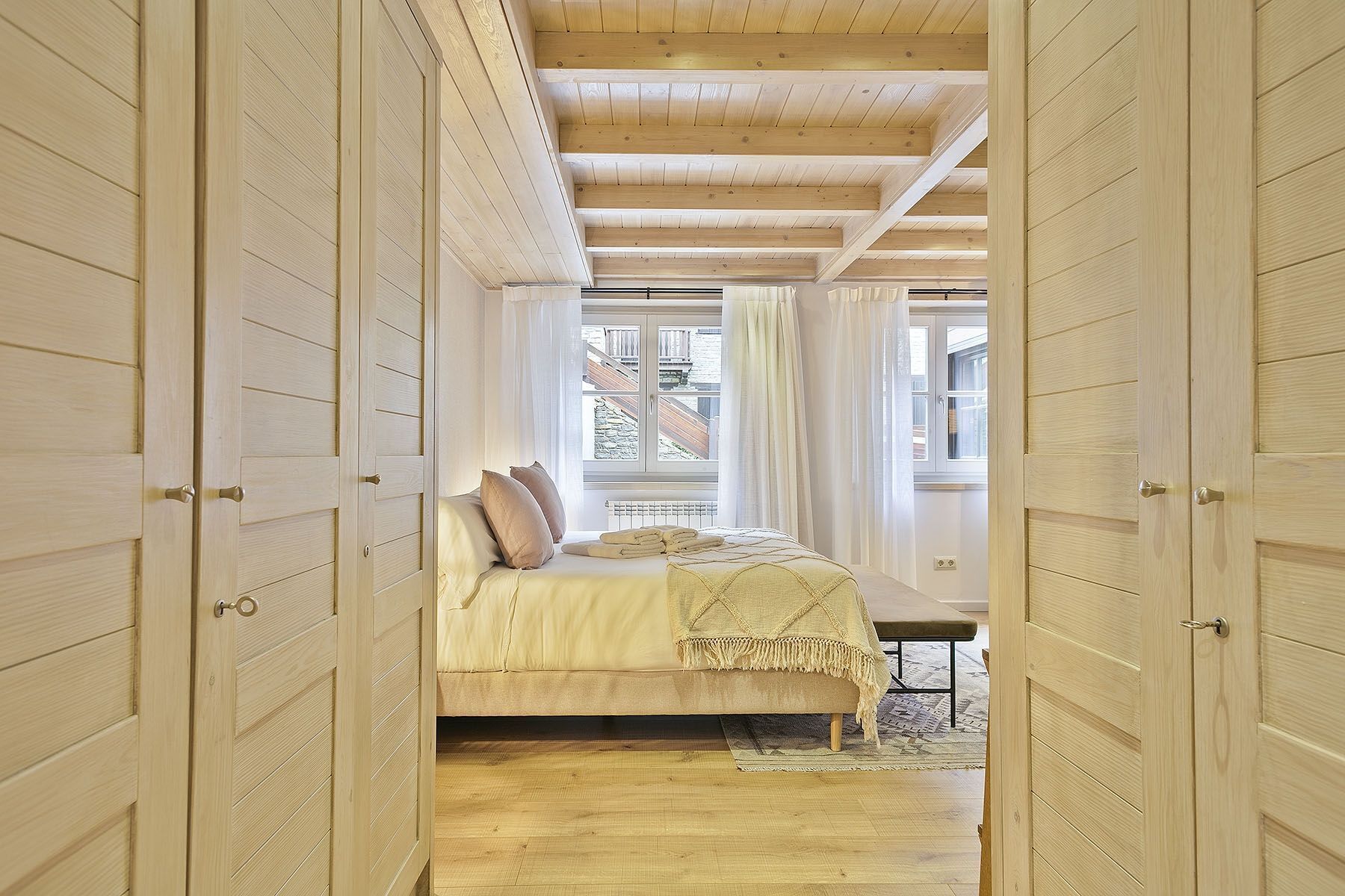 A bedroom with a bed, a window with curtains, and wooden walls.