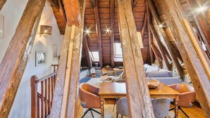 An attic room with exposed wooden beams, a dining table, chairs, and a sofa. - Luderna - Casa Coto Moreu (Betren)