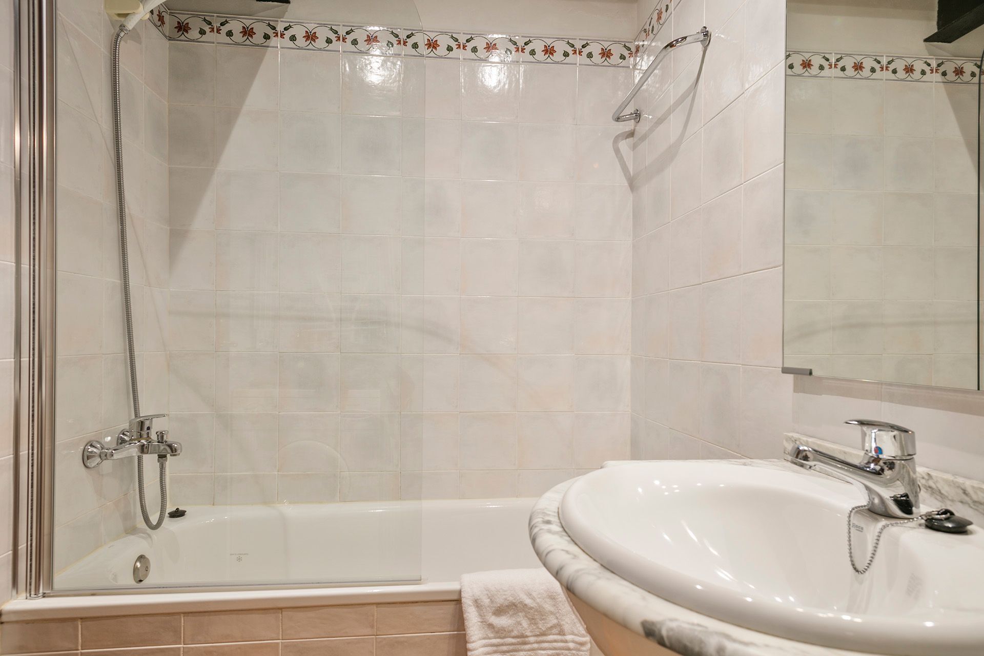 Un baño con ducha de vidrio, lavamanos blanco y espejo.