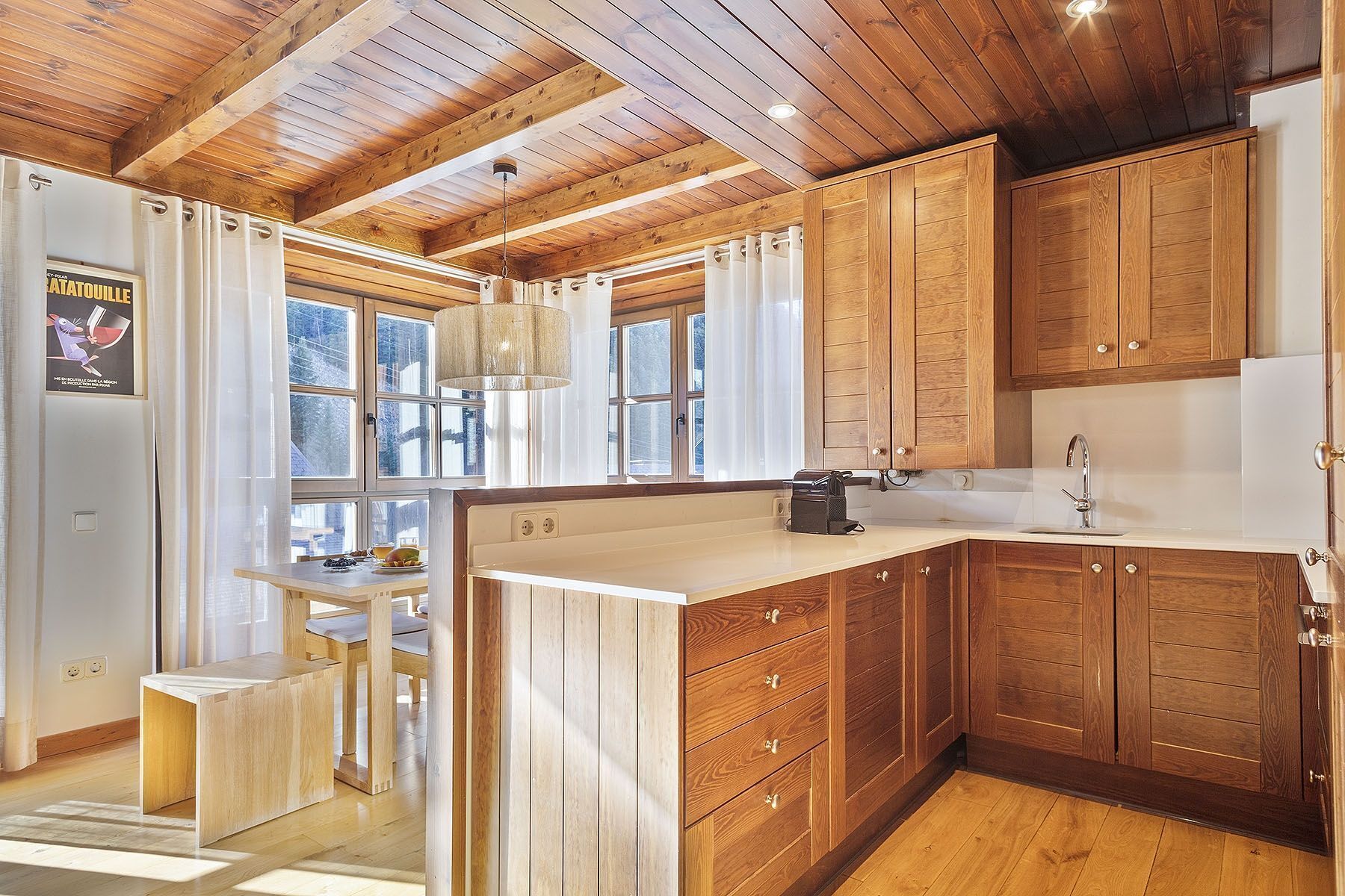 A kitchen with wooden cabinets, a sink, and a window with curtains.